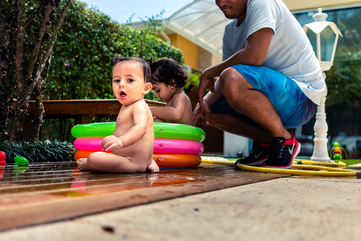 Fotografia Documental de Família em Cotia, Granja Viana, São Paulo, família Galli com filho, bebê, criança de um ano de idade. Momentos em família no café da manhã e brincando com as crianças com água. Bateria completa com os filhos.
