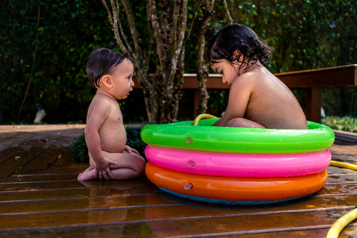 Fotografia Documental de Família em Cotia, Granja Viana, São Paulo, família Galli com filho, bebê, criança de um ano de idade. Momentos em família no café da manhã e brincando com as crianças com água. Bateria completa com os filhos.