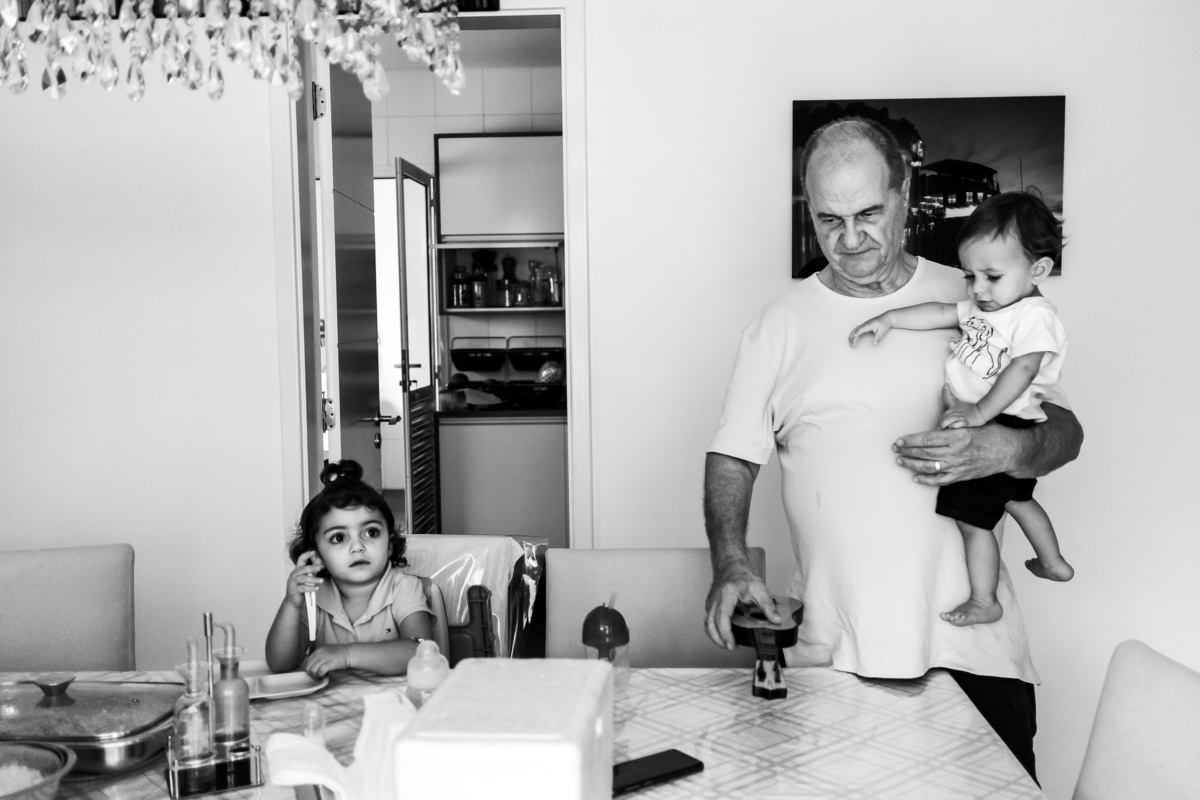 Fotografia Documental de Família em Cotia, Granja Viana, São Paulo, família Galli com filho, bebê, criança de um ano de idade. Momentos em família no café da manhã e brincando com as crianças com água. Bateria completa com os filhos.