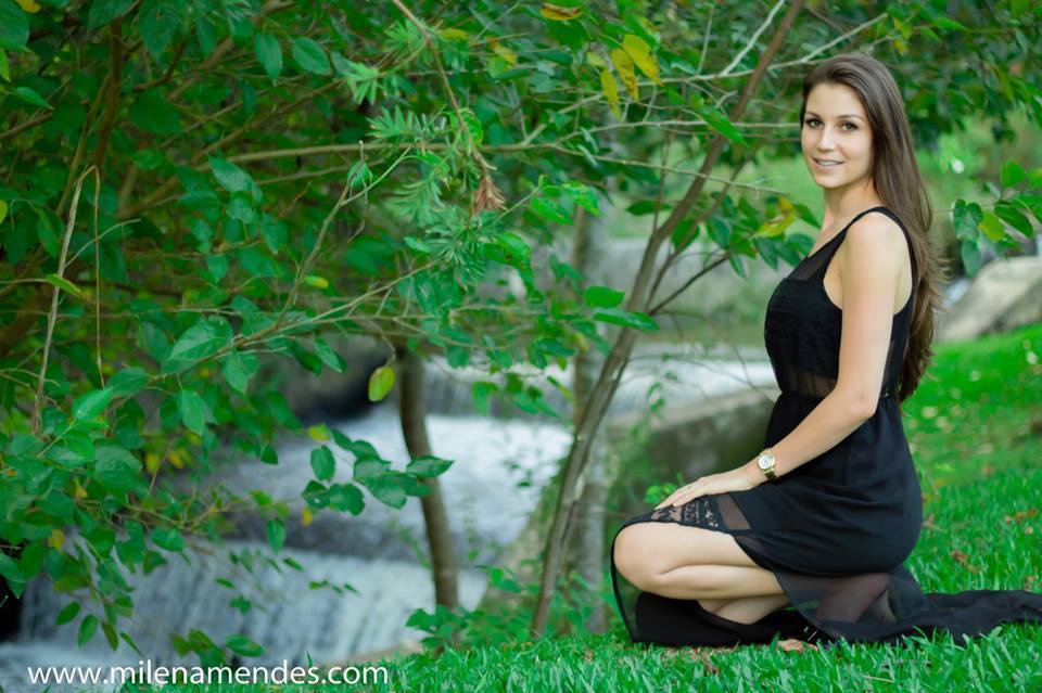 Book feminino Curitiba Milena Mendes, mulher fotografada aparece, cachoeira e grama onde está em posição de agachada  