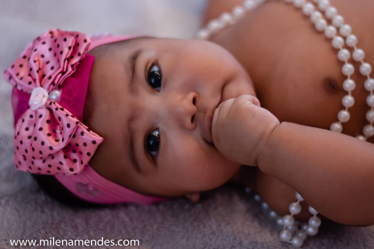Ensaio Acompanhamento de Bebê, onde bebê coloca mão na boca e é fotografada 