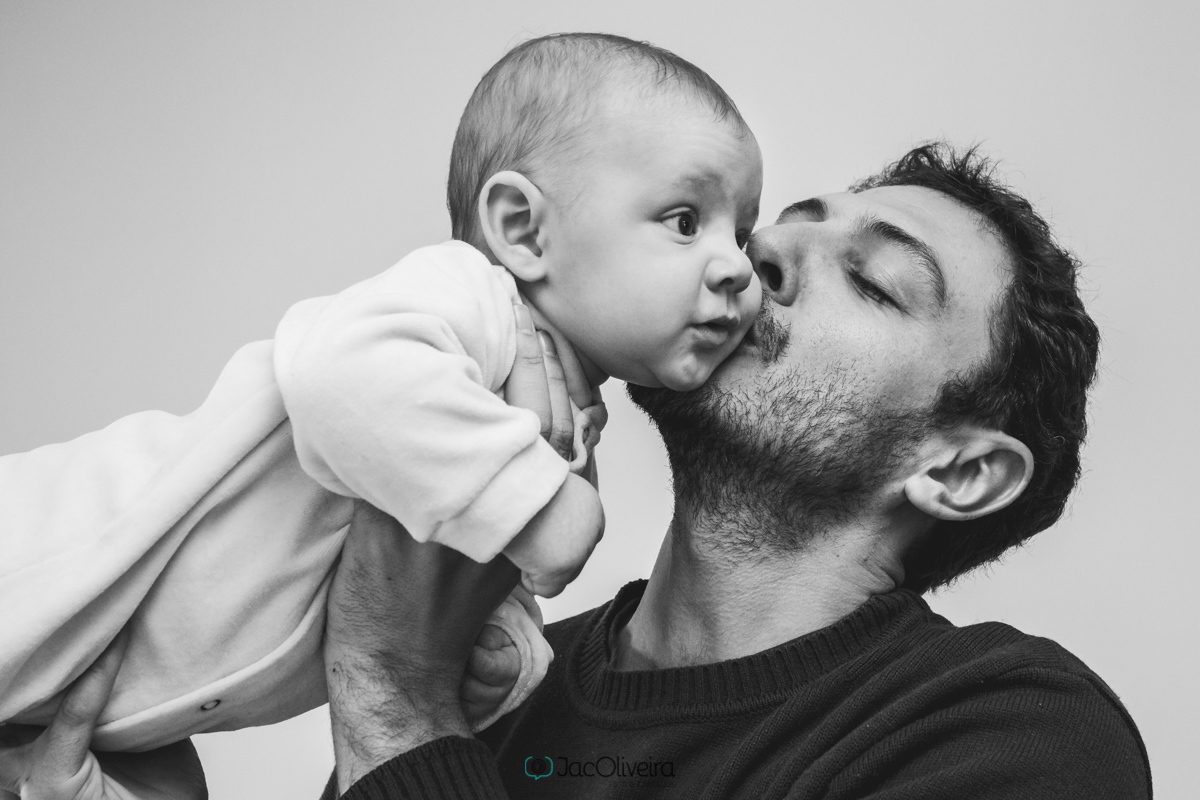pai beijando rosto do bebê preto e branco