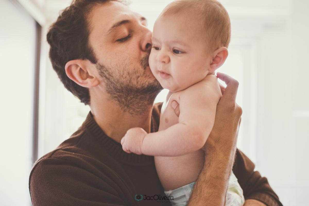 papai com bebê de fralda no colo e beijando 