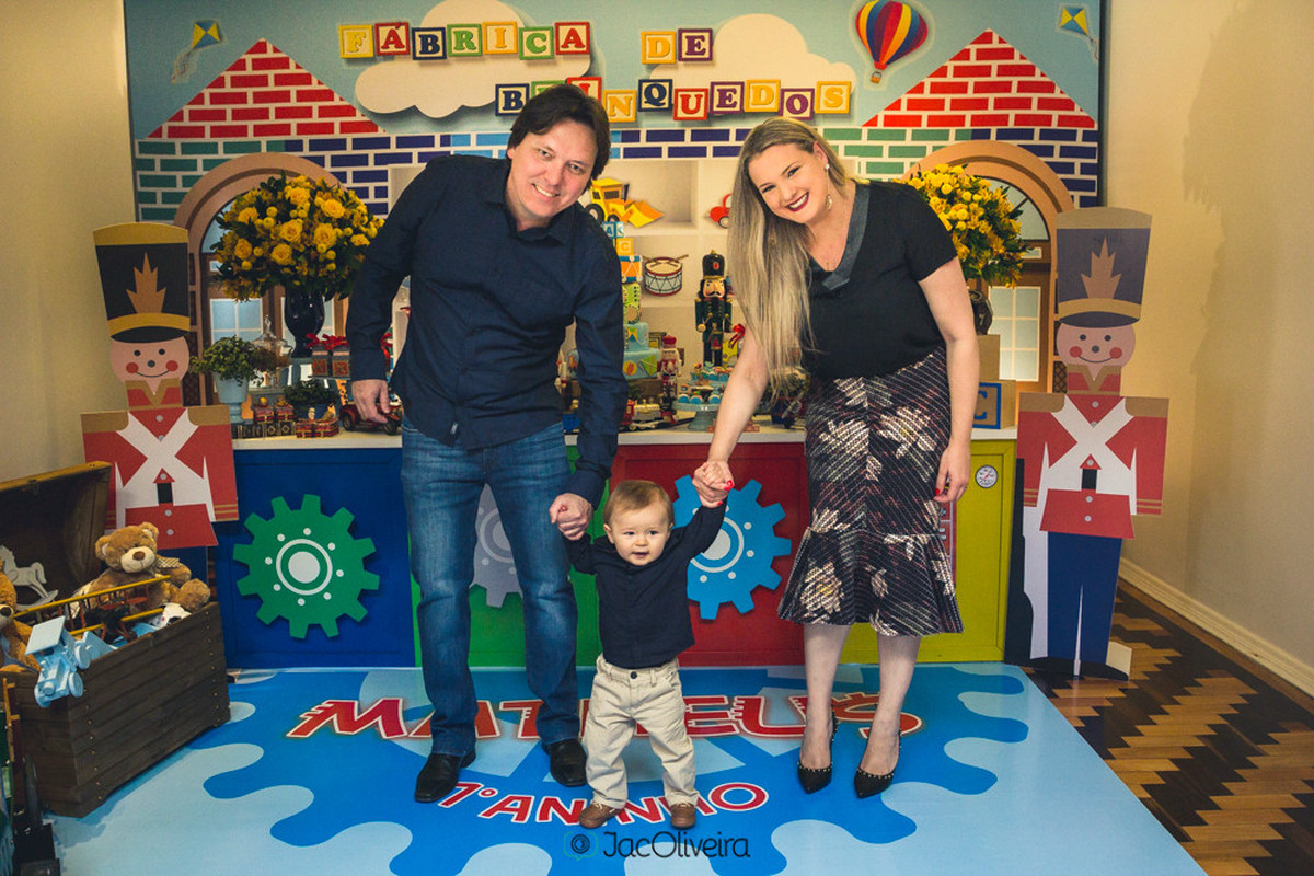 pais e criança em frente a mesa do bolo