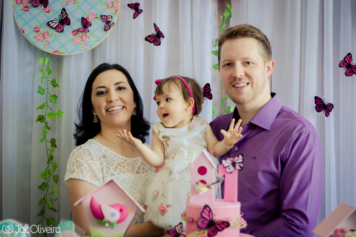 isabela e os pais na mesa do bolo