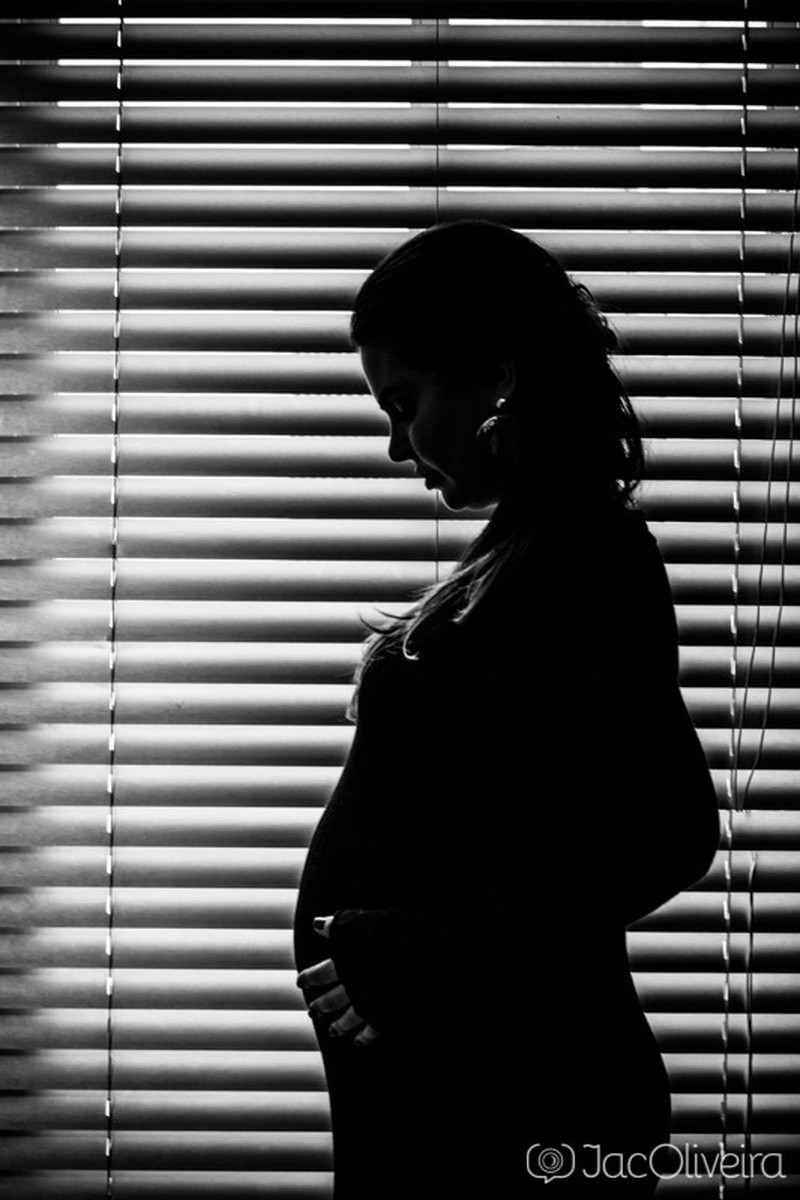gestante na sombra da persiana
