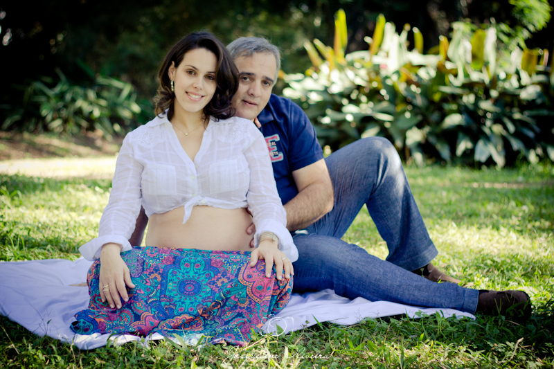 gestante e marido sentados sobre toalha