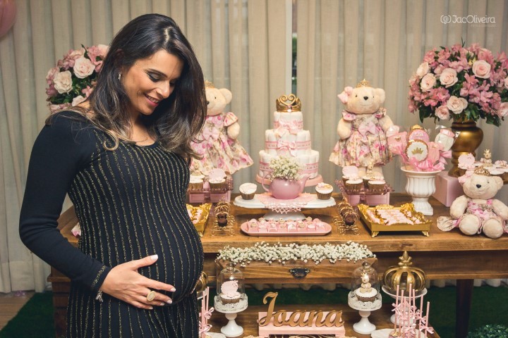fotografia gestante no chá de bebê em frente mesa de doces