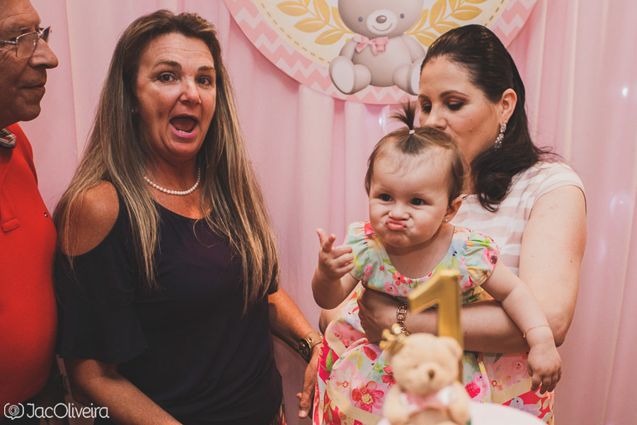 menina vestido florido e rosa no colo da mãe fazendo careta aniversario infantil