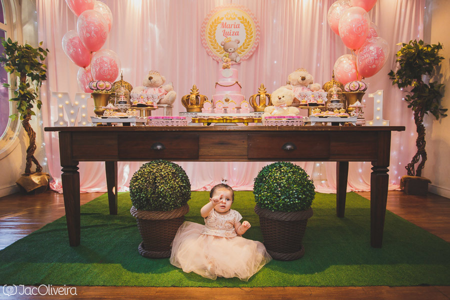 maria luiza sentada em frente a mesa do bolo de aniversário