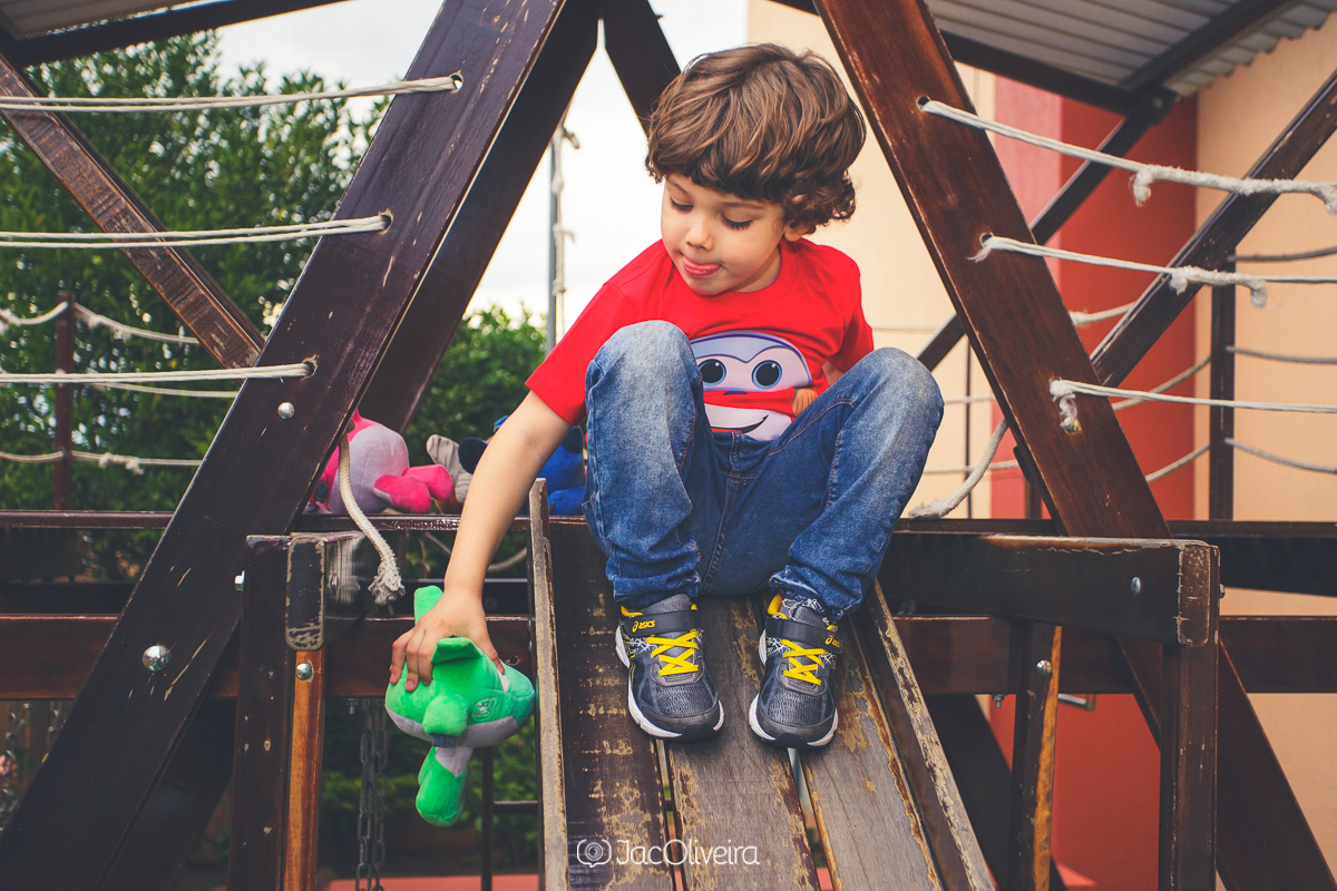 menino brinca com pelúcia no parquinho