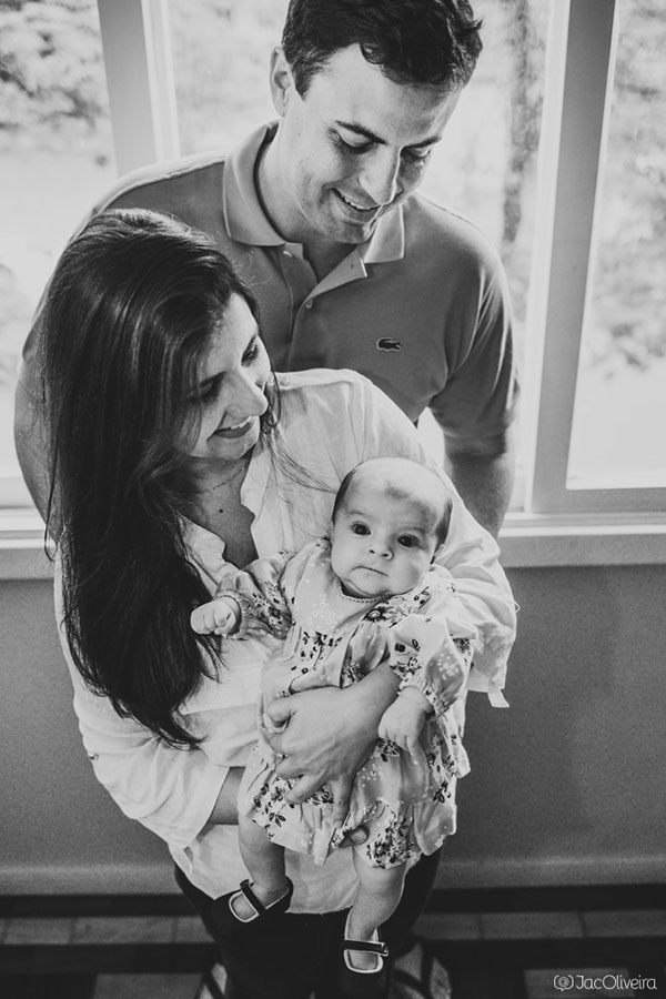 pais com a bebê cecília foto em frente da janela
