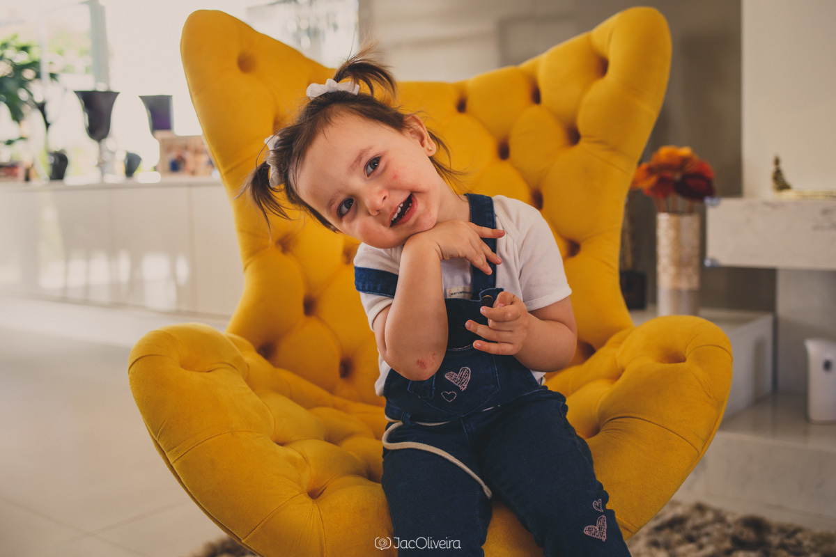 fotógrafa de família e infantil em porto alegre; menina faz pose na poltrona amarela