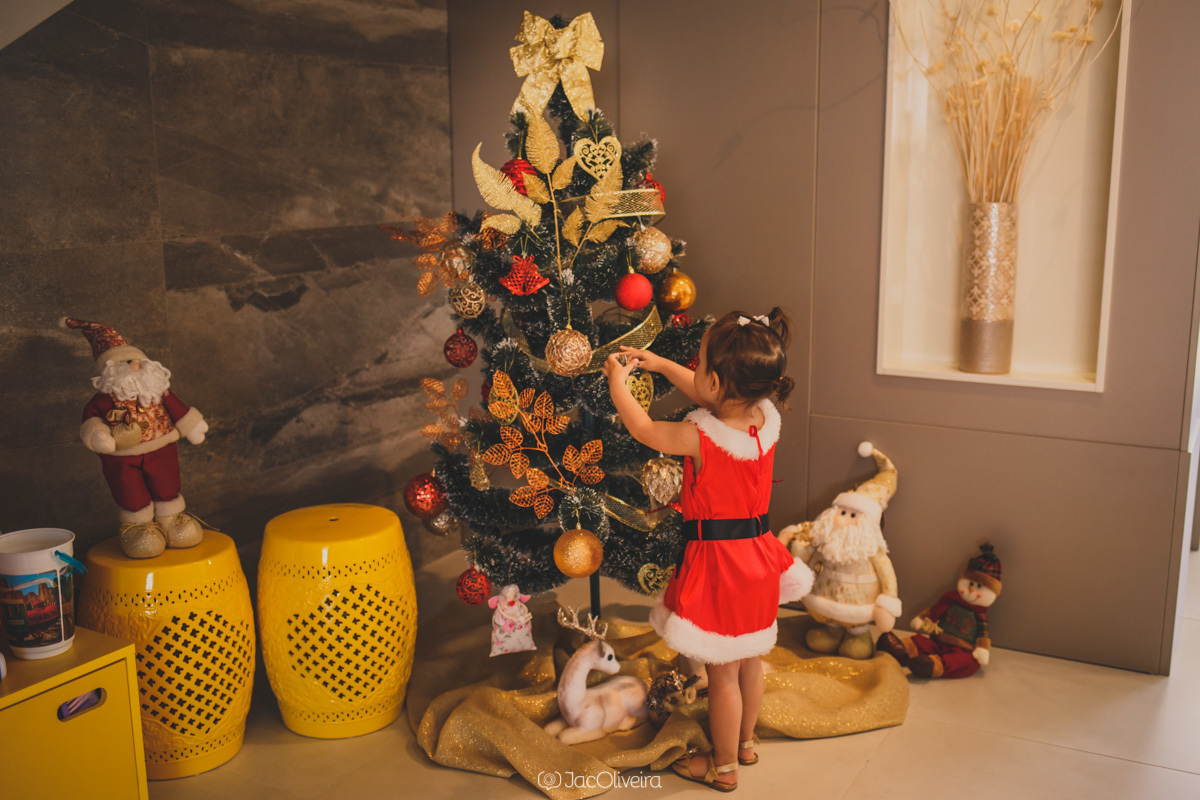 menina arruma arvore de natal com vestido mamãe noel fotografia infantil porto alegre