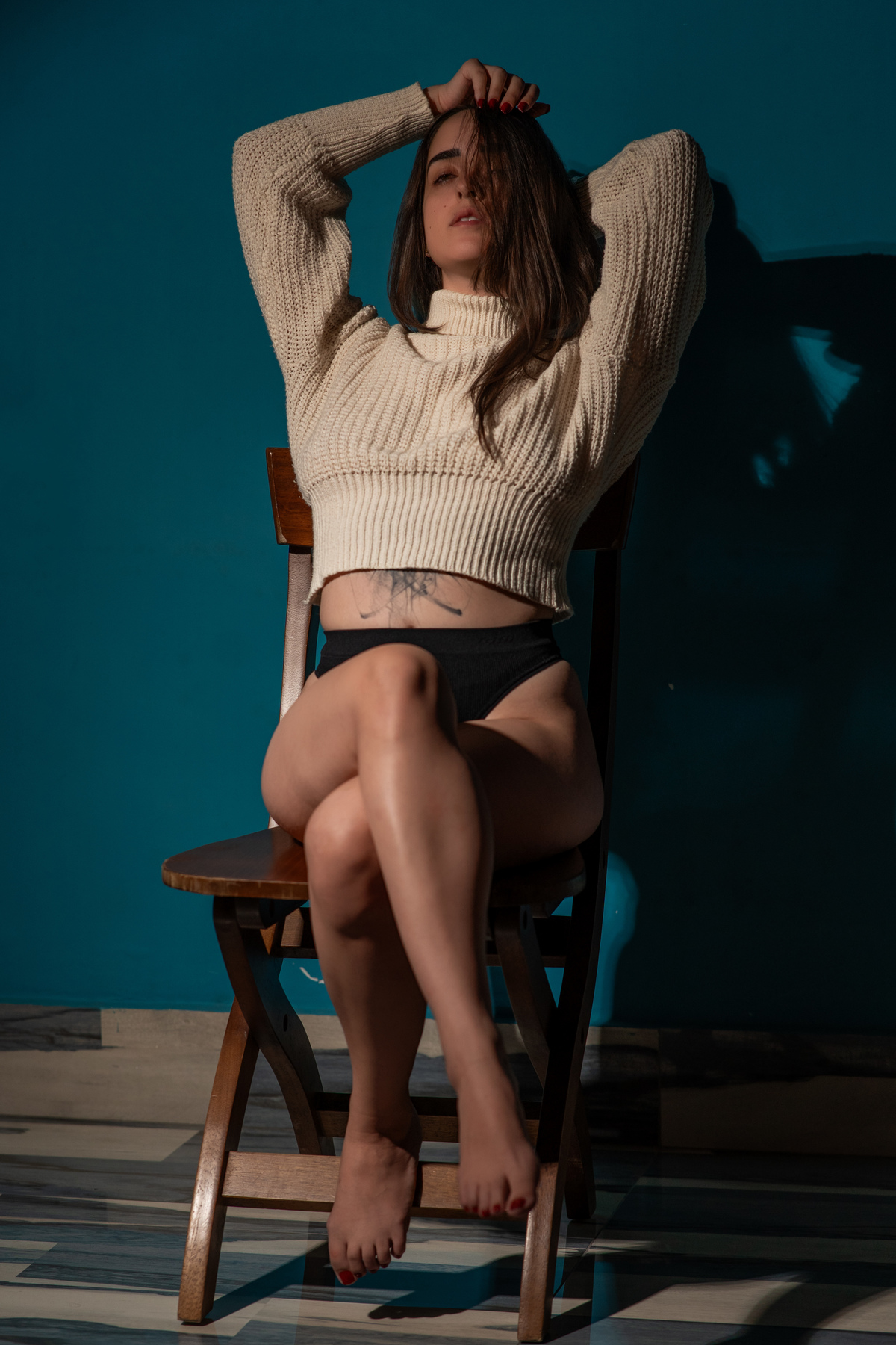 Ensaio sensual feminino em Curitiba, pose sentada com luz dramática