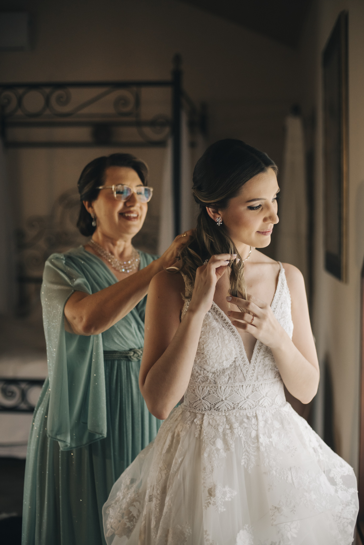 noiva com sua mae abotoando o vestido de noiva