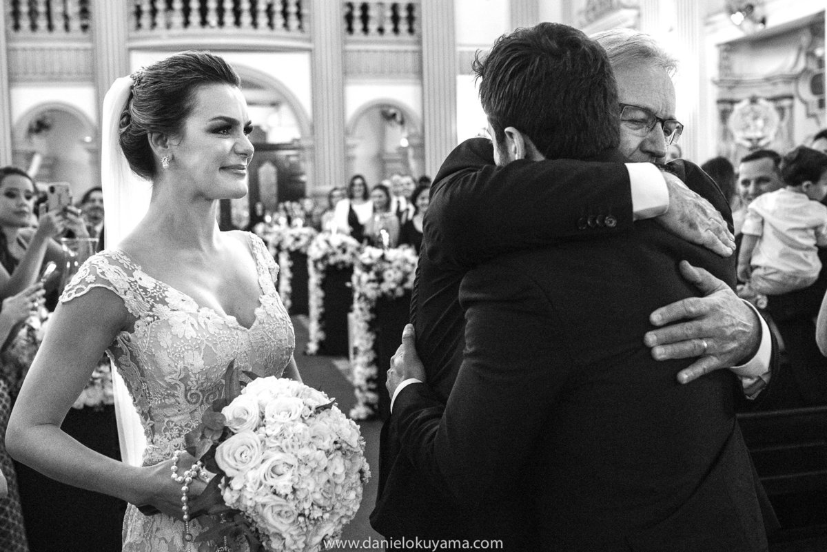 a noiva emocionada ao chegar no altar com o abraço de seu pai e do seu noivo com muito amor e carinho 