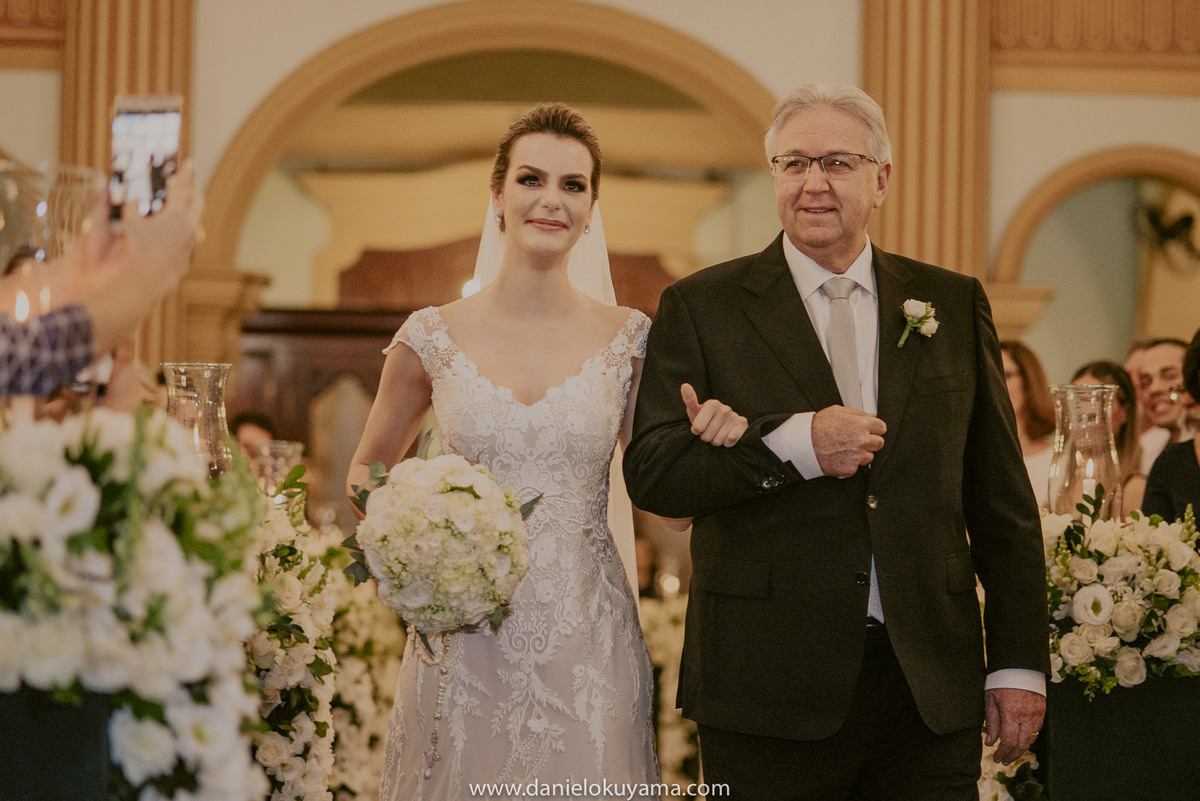 a noiva com o seu pai a caminho de encontrar o noivo durante esse lindo casamento 
