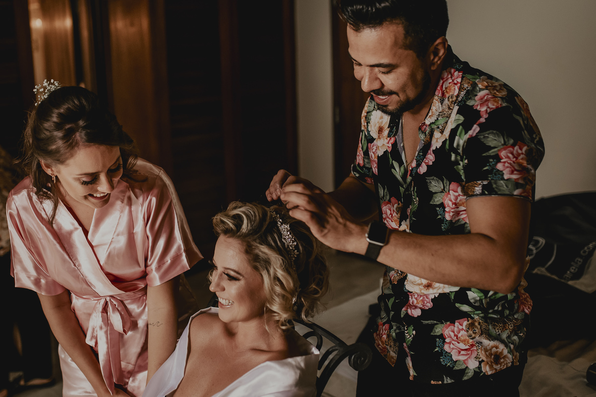 a noiva se maquiando com suas irmas em making of na casa de praia durante a preparação do casamento em sp