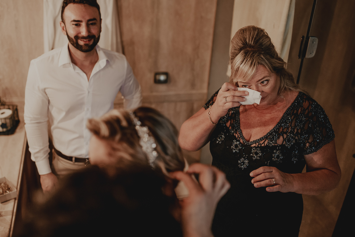 um momento de emoção e alegria da mãe da noiva emocionada antes da preparação do making of da noiva na fotografia de casamento na praia sp