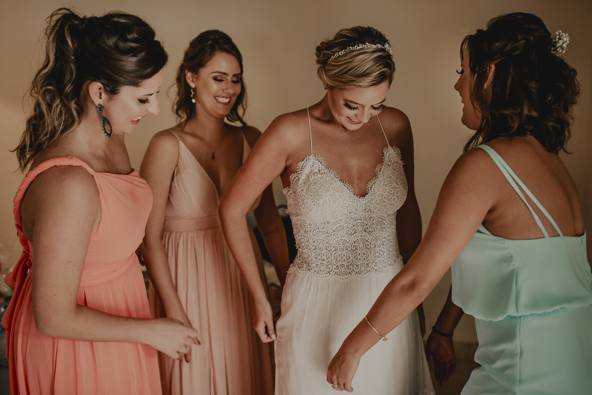 fotografia de casamento sp da noiva com as madrinhas durante momento espontâneo com sorrisos arrumando seu vestido de noiva antes da cerimonia de casamento na fotografia de daniel okuyama 
