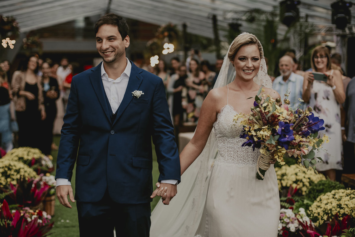 a entrada dos noivos que se casaram na praia no litoral de sp com uma decoração colorida bem estilo praiana minutos antes do say i do