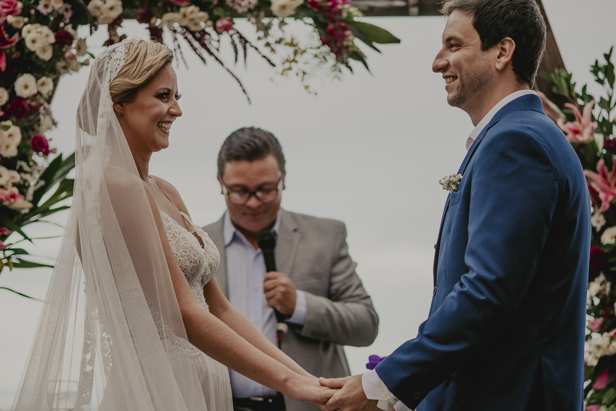 a benção durante a cerimonia de casamento com uma decoração um arco rústico e alegre para o grande dia do casamento na praia do litoral de sp