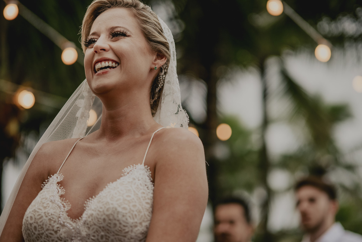 o sorriso espontâneo da noiva durante o casamento na praia pé na areia com uma fotografia autentica e divertida com muita alegria e felicidade