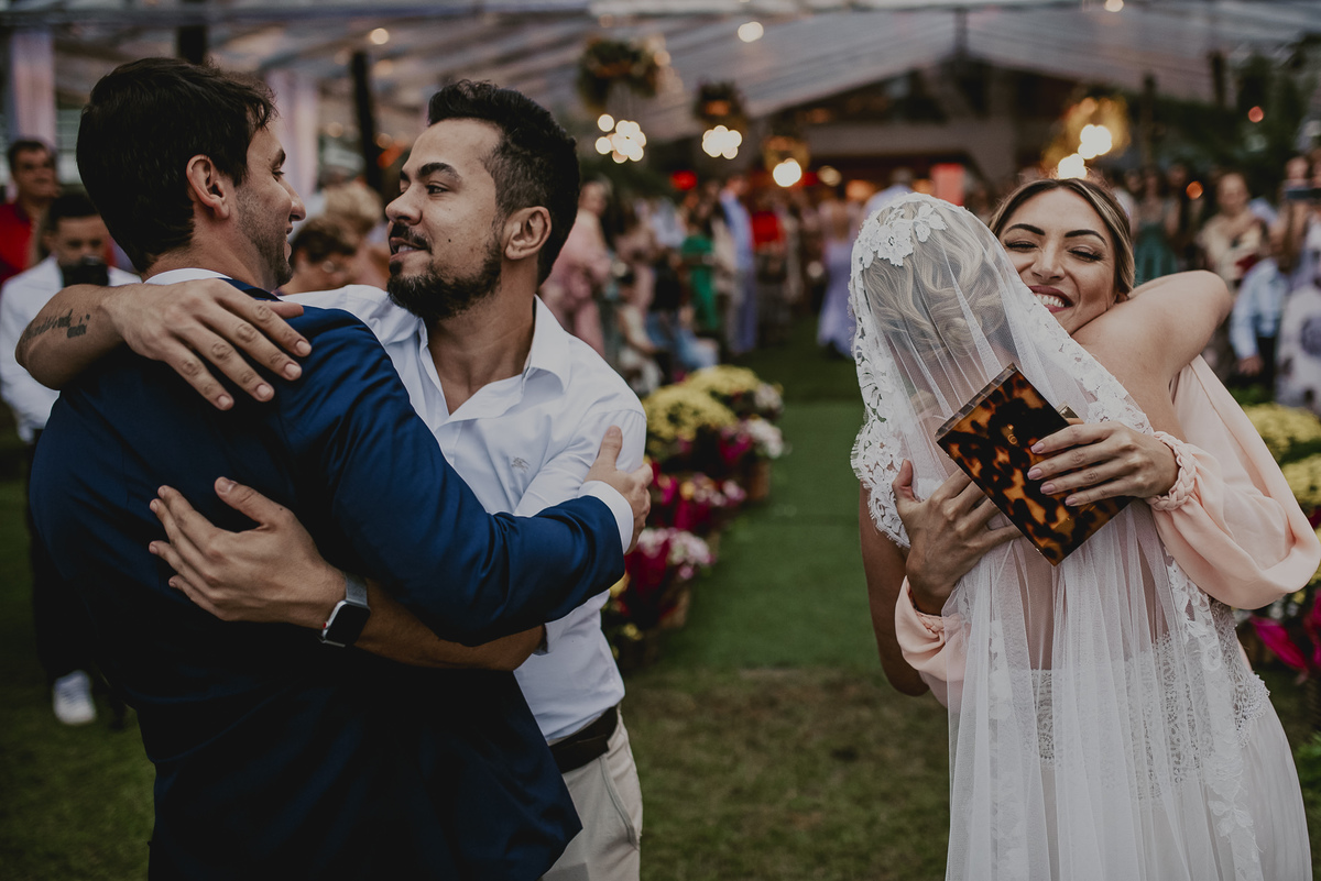 os cumprimentos em um casamento é sempre um momento emocionante, onde os noivos abraçam os pais, os padrinhos, as madrinhas e os convidados mais queridos no casamento pé na areia na praia em sp