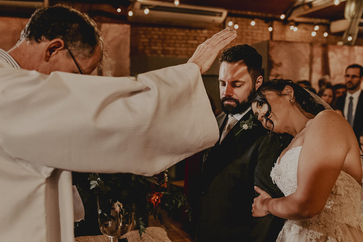 a fotografia de casamento durante a benção do padre no casamento realizados no celeiro quintal e fotografado por Daniel Okuyama Fotografia, fotografo de casamentos em sp