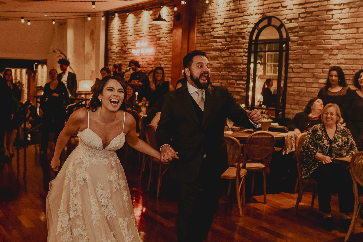 a entrada dos noivos durante a festa do casamento uma fotografia mais espontanea do casamento com sorrisos dos noivos e a alegria verdadeira