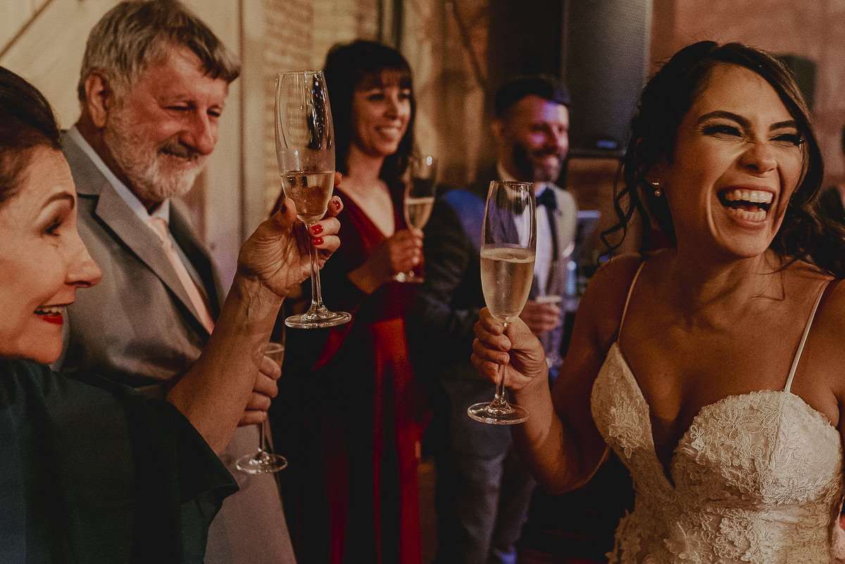 a fotografia do brinde dos noivos em um casamento com o sorriso da noiva no celeiro quintal em ap