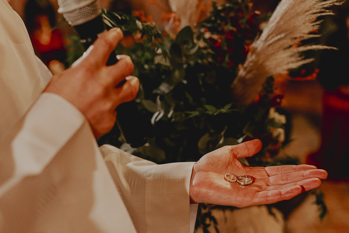 fotografia dos detalhes das alianças durante a cerimonia de casamento no celeiro quintal sp 
