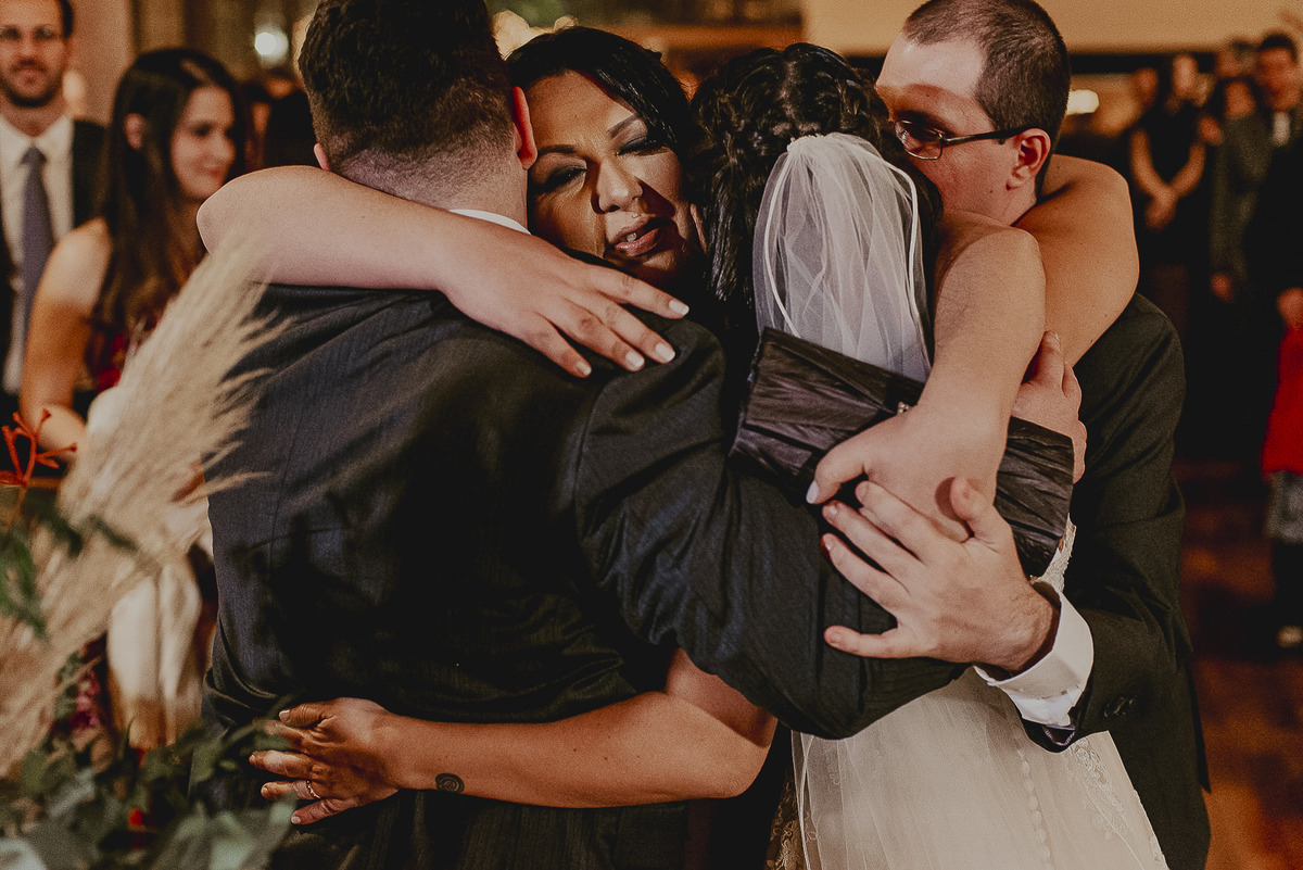 fotografo de casamento em sp daniel okuyama fotografa os noivos abraçados e emocionados durante os cumprimentos do casal com seus pais no casamentos realizado no Celeiro Quintal em SP