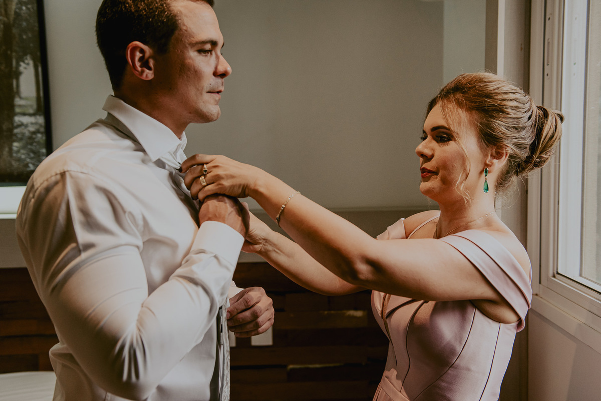 fotografia documental de casamento pelo melhor fotógrafo do Brasil daniel okuyama. O noivo se arrumado com a sua mãe em momento único antes do casamento no campo