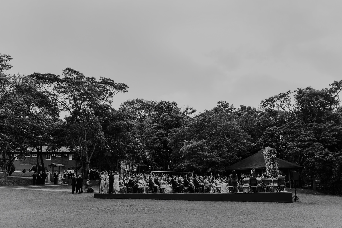 uma foto aberta mostrando todo o casamento na fazenda, mostra onde foi o casamento, como estava o tempo e todas as pessoas que estavam no casamento. uma foto incrível de casamento no campo 