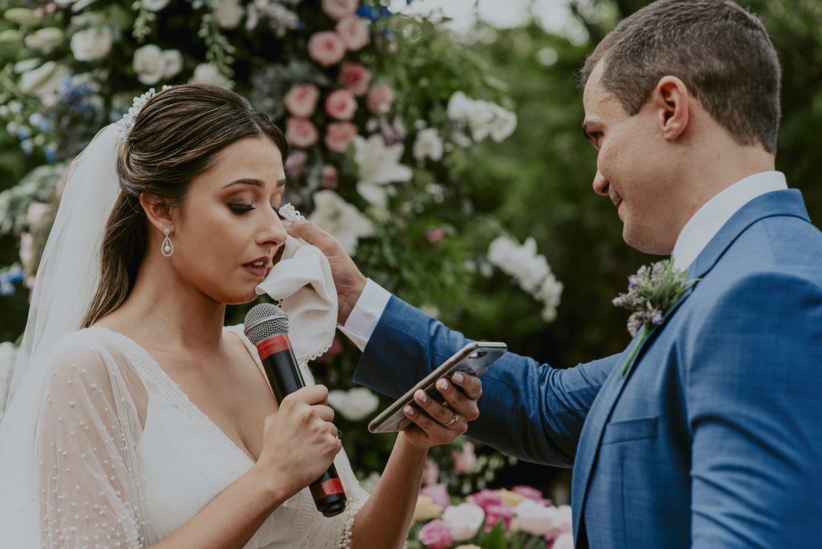 linda foto do noivo enxugando as lagrimas da noiva enquanto ela lia seus votos para ele. um dos momentos mais emocionantes de um casamento ao ar livre é esse. uma foto perfeita de lembrança para os noivos do casamento do daniel okuyama fotografia