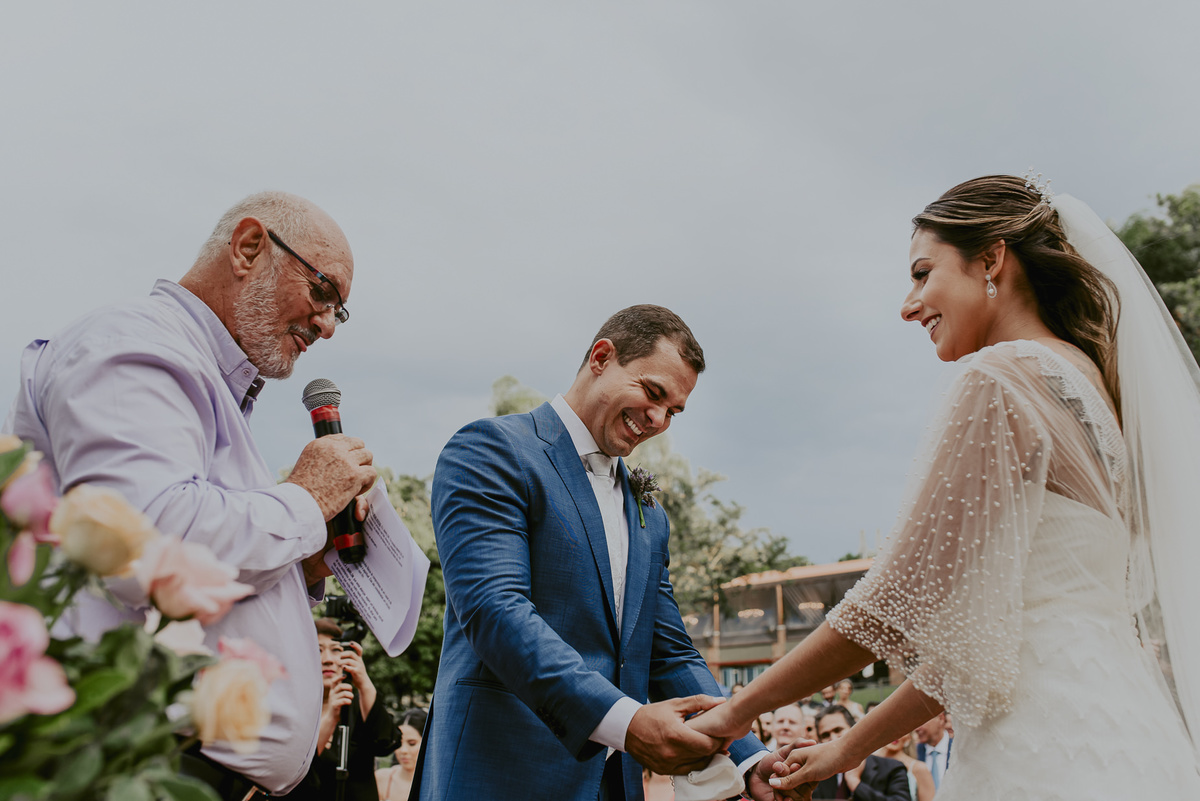 os noivos de mãos dadas representando o carinho e o amor junto com o celebrante do casamento na fazenda