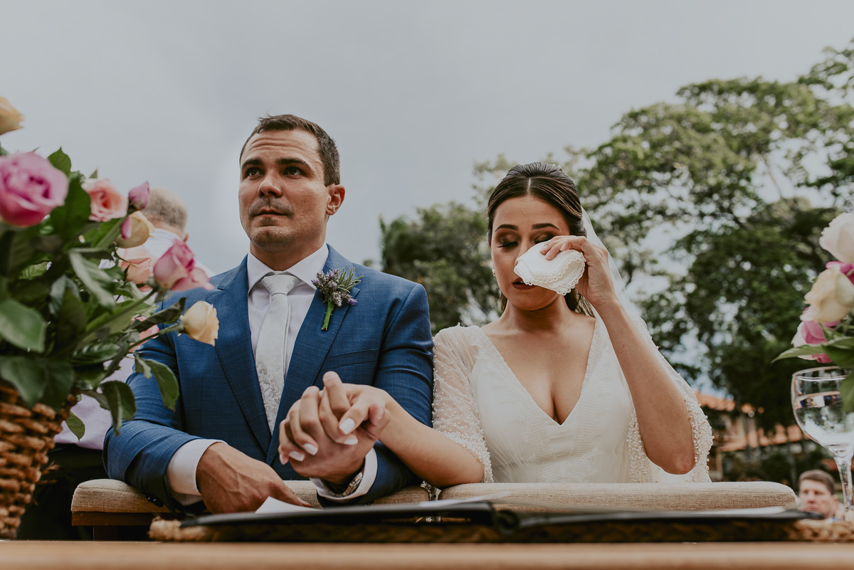 A emoção dos noivos no altar decorado ao ar livre durante a cerimonia de casamento. fotografa espontanea de casamento do melhor fotografo de casamento de sp daniel okuyama