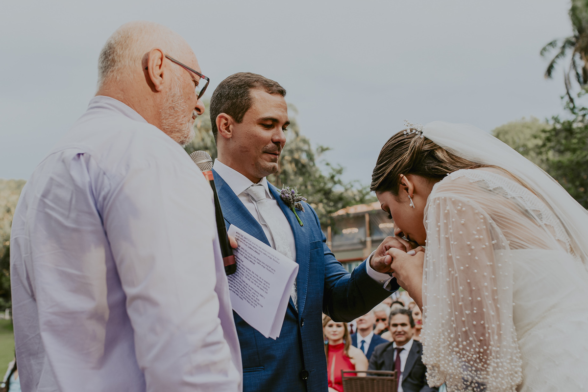 o beijo da noiva na aliança do noivo muito amor e felicidade dos noivos e do celebrante do casamento ao ar livre no campo com um dia lindo de sol