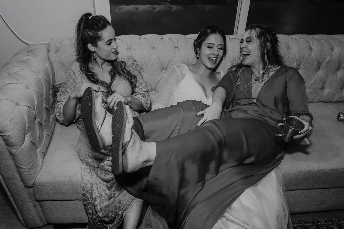 momento registrado pelo daniel okuyama da noiva com suas amigas e madrinhas no final da festa do casamento com os chinelos dando uma relaxada no lounge dafesta do casamento. registro espontaneo feito pelo melhor fotografo do brasil
