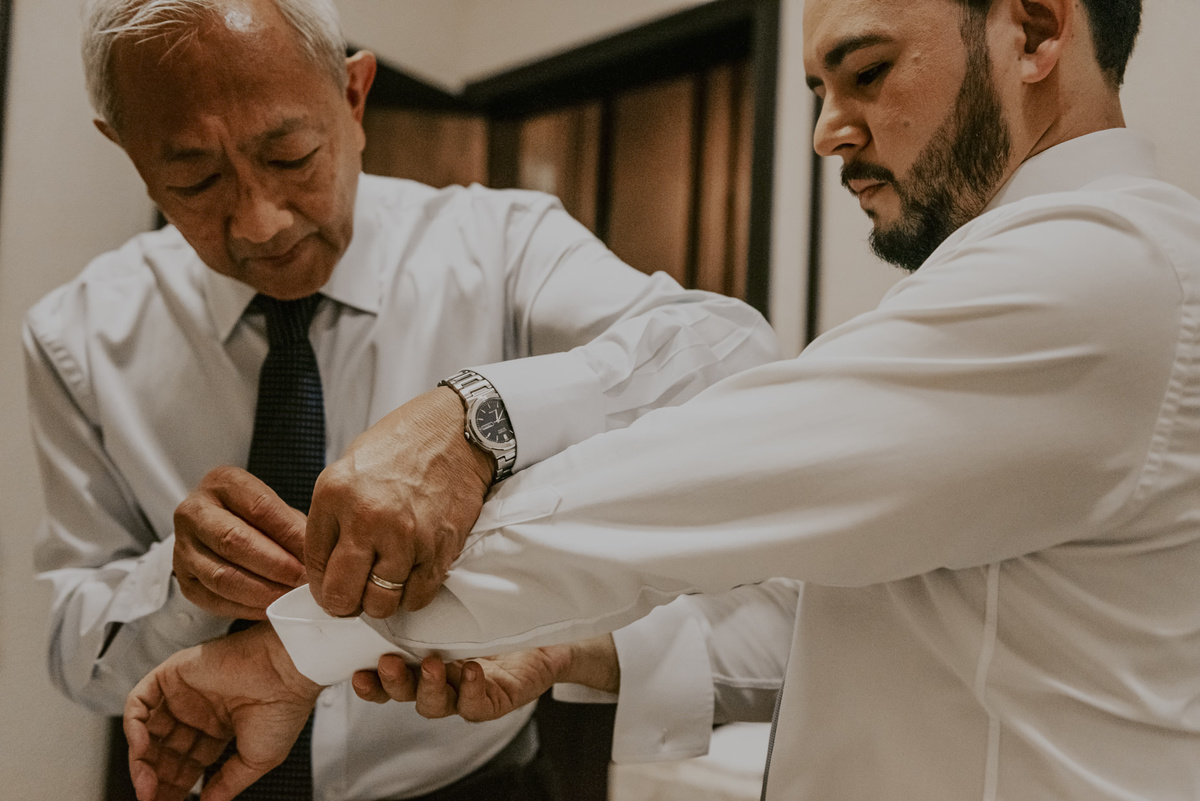 o pai do noivo ajundando a abotoar a camisa, foto classica e atemporal no dia do noivo, na barbearia.