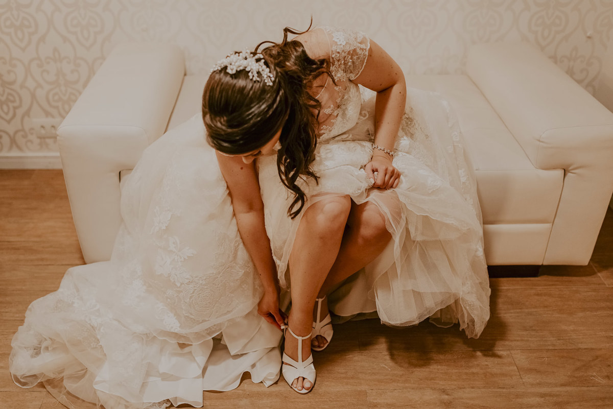 a noiva colocando os sapatos pois esta chegando o grande momento desse casamento realizado na capela da pu sp