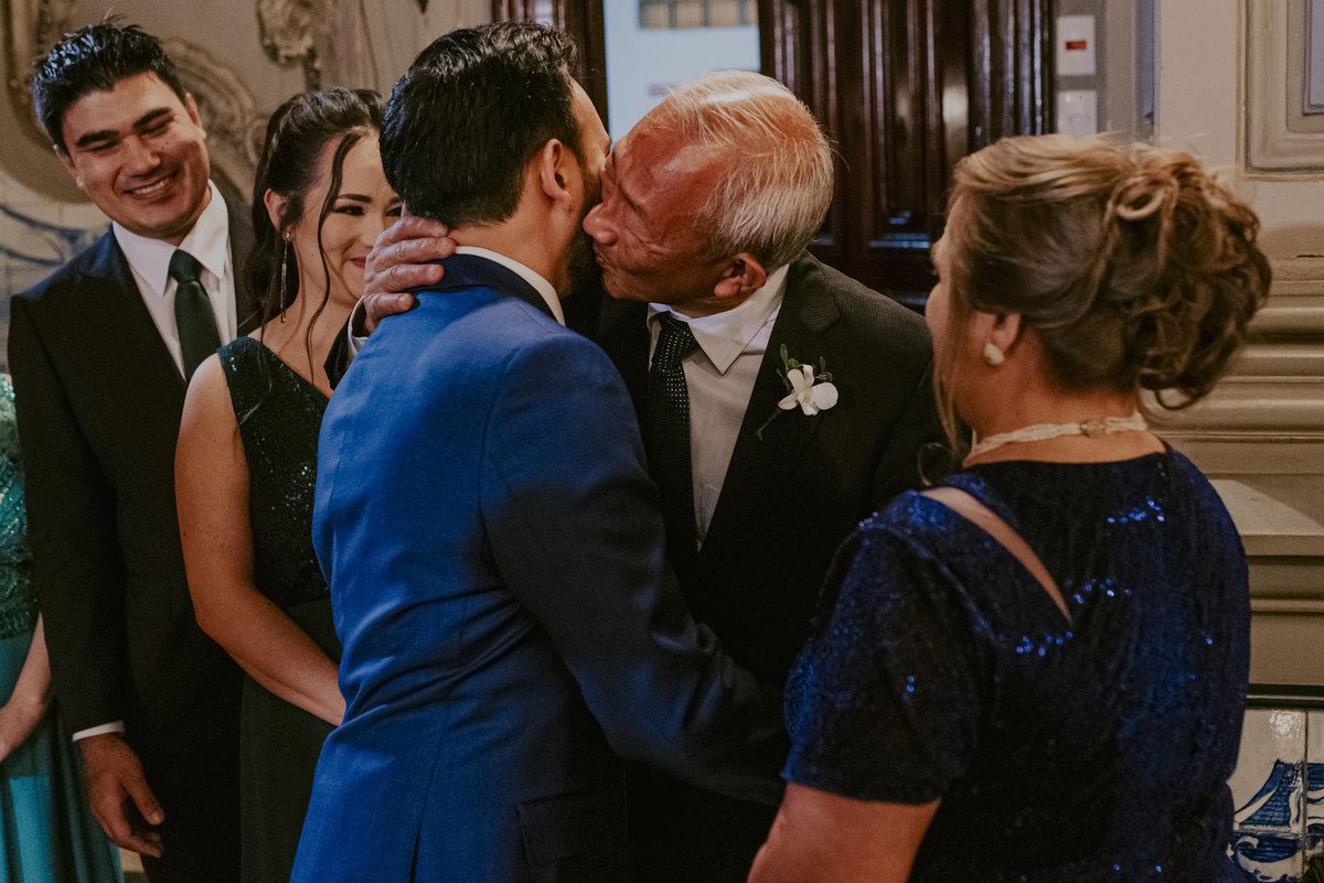 o pai do noivo dando um beijo muito carinhoso durante a cerimonia do casamento na capela da pu sp