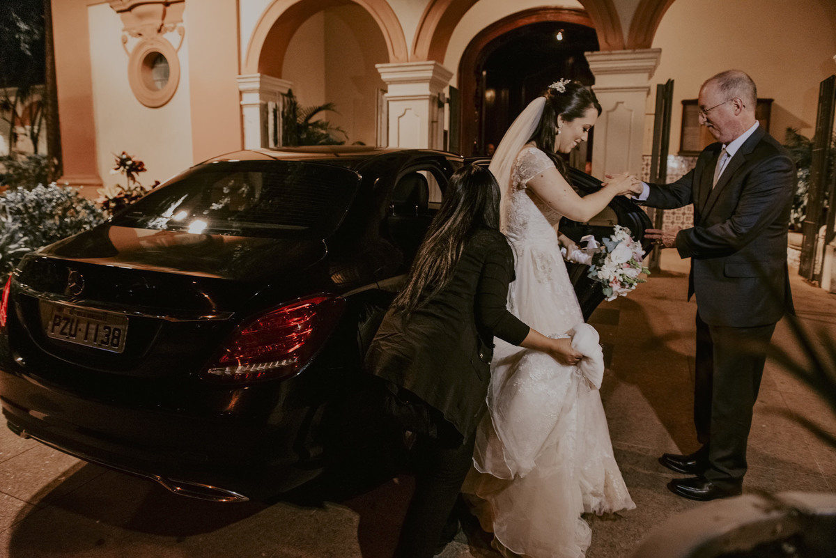a assessora do casamento juntamente com a  ajuda do seu pai  a noiva a descer do carro e se preparar para a entrada na igreja