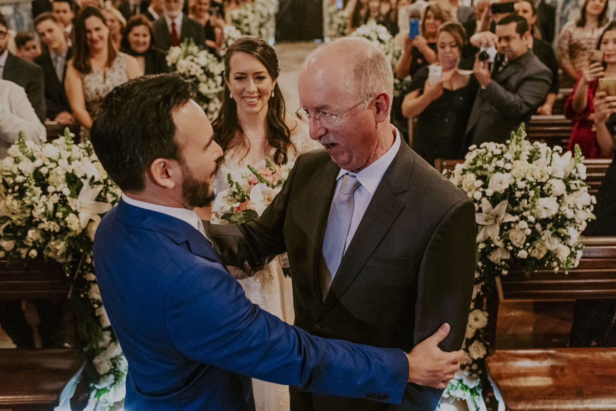 um abraço cordial e carinhoso do noivo com seu sogro, o pai da noiva que a levou até o altar da capela da puc sp 