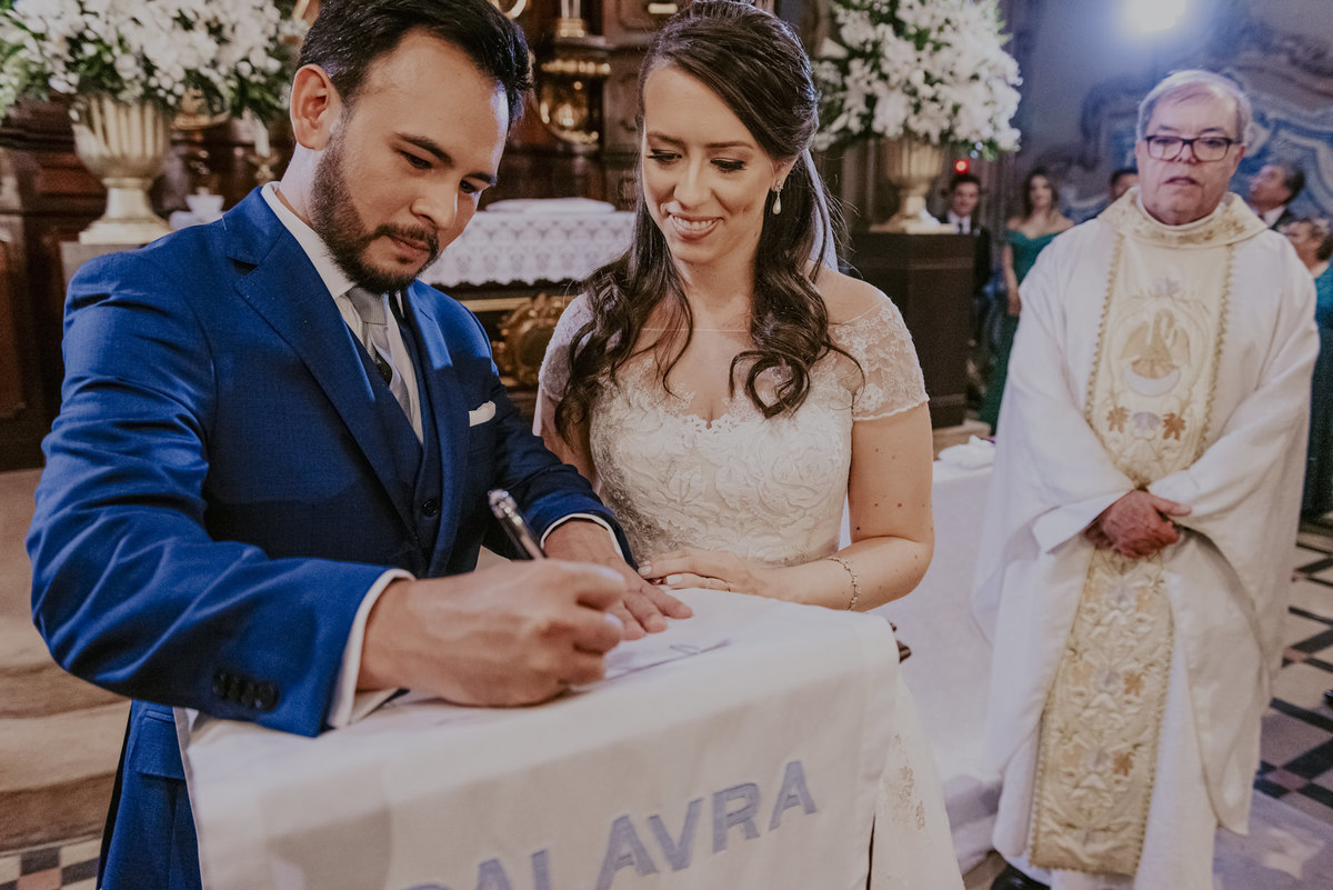 os noivos assinam perante Deus em matrimonio na igreja perante a benção do padre na capela da puc