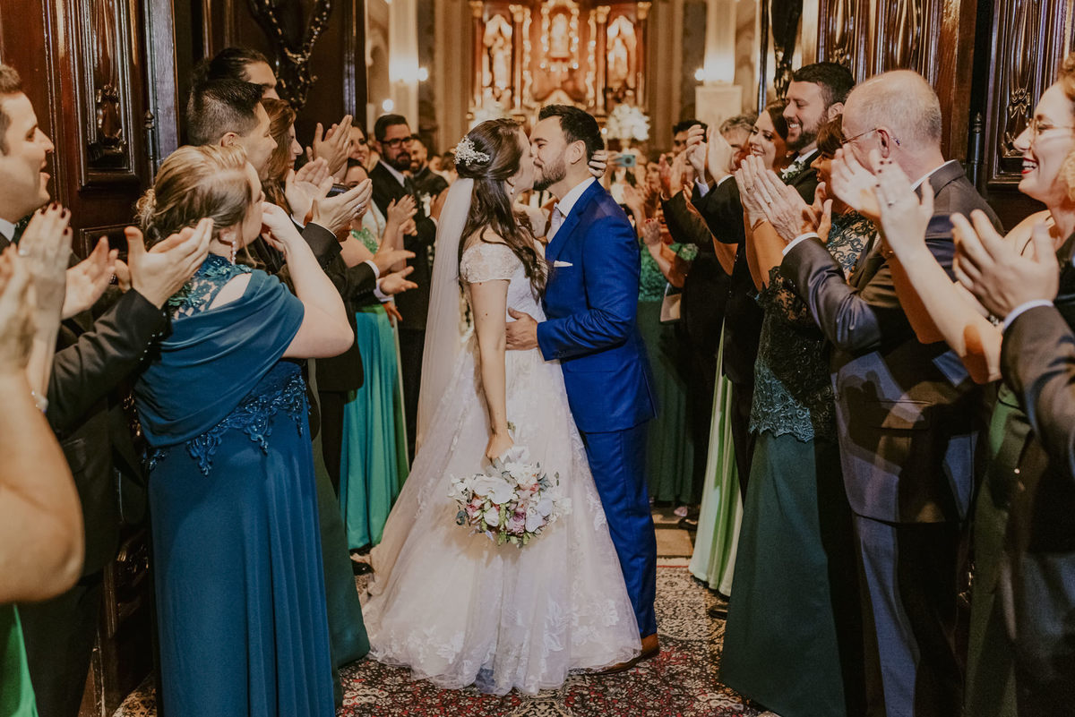 o singelo beijo dos noivos na port da igreja com todos os convidados aplaudindo, uma linda foto de casamento fotografado pelo melhor fotografo de sp daniel okuyama fotografia