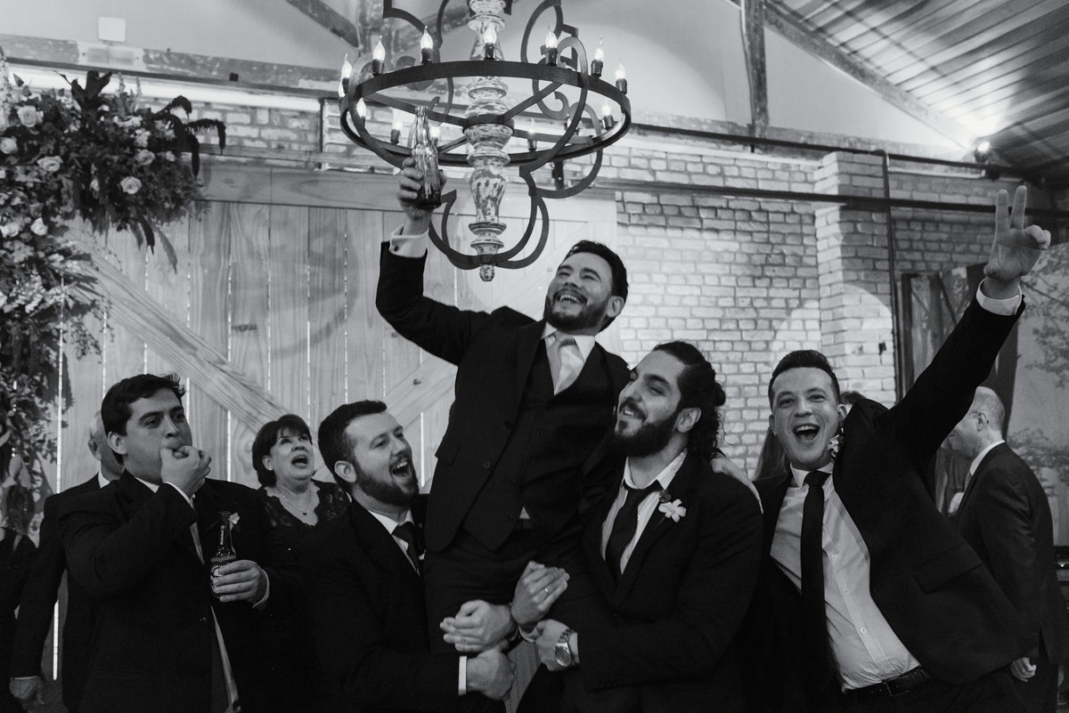 descontração do noivo com seus padrinhos pegando ele no colo uma fotografia única e espontânea