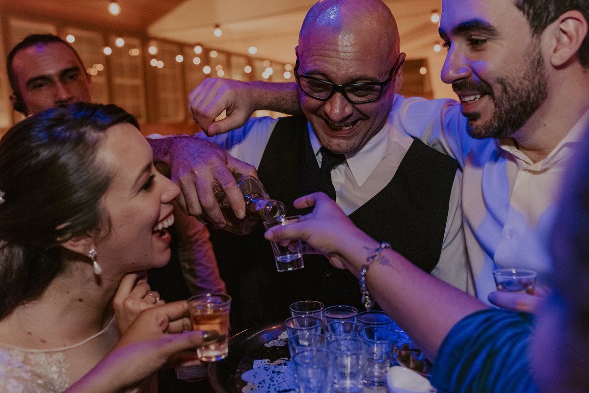 o garçom servindo uma bebida para os noivos no meio da balada do casamento que foi pura diversão gerando as fotos mais espontâneas do fotografo de casamento sp 